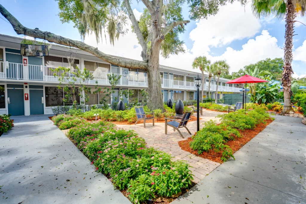 Exterior photo of Champions Village apartment patio with seating area and greenery