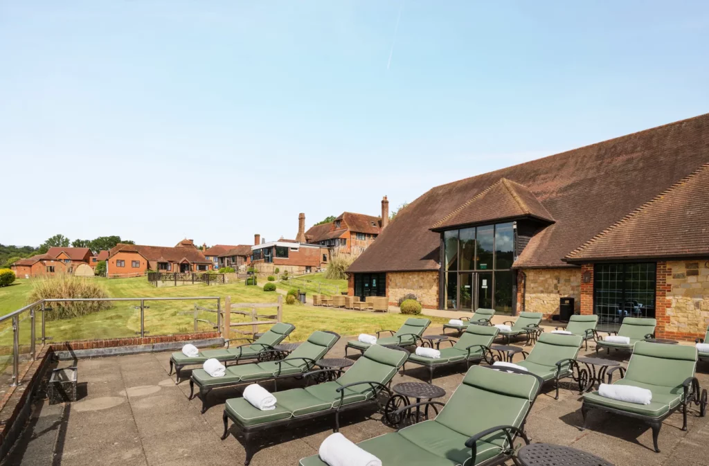 Outdoor relaxation area at Lythe Hill Hotel with sunbeds and garden view